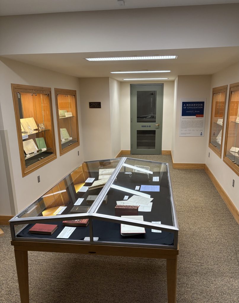 An exhibit outside of Bertrand Library's Special Collections, showing a glass case with artifacts and documents inside.
